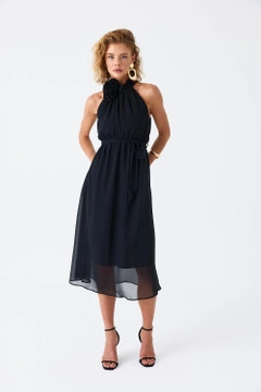 Bir model, Tuba Butik toptan giyim markasının tbu11782-halter-neck-chiffon-midi-dress-black toptan Elbise ürününü sergiliyor.