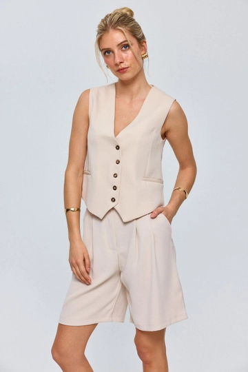 Bir model, Tuba Butik toptan giyim markasının  V Yaka Düğmeli Kadın Yelek - Bej
 toptan Yelek ürününü sergiliyor.