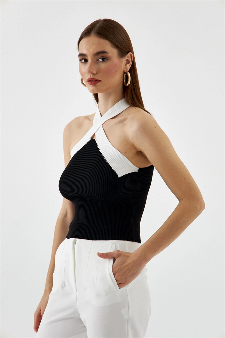 Bir model, Tuba Butik toptan giyim markasının TBU10602 - Women's Cross-Strap Knitwear Blouse - Black toptan Bluz ürününü sergiliyor.