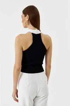 Bir model, Tuba Butik toptan giyim markasının TBU10602 - Women's Cross-Strap Knitwear Blouse - Black toptan Bluz ürününü sergiliyor.