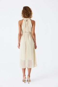 Bir model, Tuba Butik toptan giyim markasının tbu11770-halter-neck-chiffon-midi-dress-beige toptan Elbise ürününü sergiliyor.