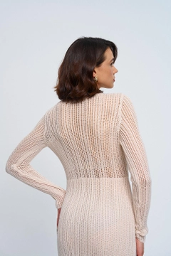 Bir model, Tuba Butik toptan giyim markasının tbu12766-openwork-long-knitted-dress-with-waist-detail-cream toptan Elbise ürününü sergiliyor.