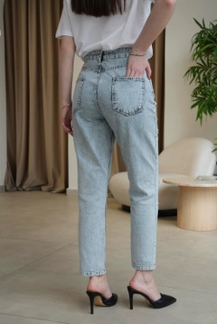 Bir model, Tuba Butik toptan giyim markasının 12697-high-waist-stone-detailed-mom-women's-jeans-blue toptan Kot Pantolon ürününü sergiliyor.