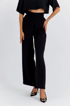 Bir model, Tuba Butik toptan giyim markasının TBU11764 - Women's Wide Leg Flowy Trousers - Black toptan Pantolon ürününü sergiliyor.