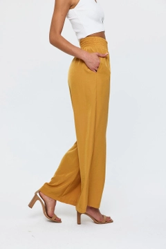 Модел на дрехи на едро носи tbu11781-women's-wide-leg-flowy-trousers-mustard, турски едро Панталони на Tuba Butik