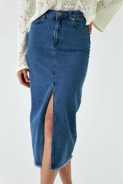 Bir model, Tuba Butik toptan giyim markasının tbu12454-midi-length-dark-denim-skirt-with-slit-detail-blue toptan Etek ürününü sergiliyor.