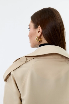 Bir model, Tuba Butik toptan giyim markasının TBU10169 - Double Breasted Short Women's Trench Coat - Beige toptan Trençkot ürününü sergiliyor.
